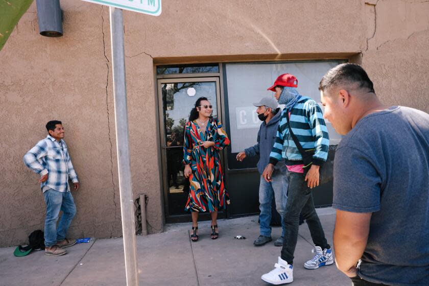 Calexico, CA - March 25: Raul Urena, the first transgender mayor of Calexico and current council member, speaks with farmworkers after they teased him from across the street for wearing a dress, near the USA-Mexico border wall on Monday, March 25, 2024 in Calexico, CA. He said that many people will make fun of what they do not know and wanted to speak with them so they could be more familiar with his choice to wear a dress. (Dania Maxwell / Los Angeles Times)