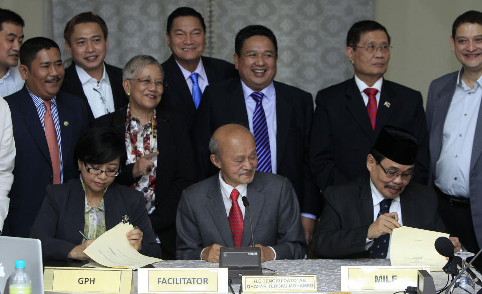 Miriam Coronel-Ferrer, seated left, chairperson of Philippine Government Peace Panel, and Mohagher Iqbal, seated right, chief negotiator for the Moro National Liberation Front (MNLF), sign documents as Malaysian facilitator Abdul Ghafar Tengku Mohamed, sitting center, witnesses after the 43rd GPH-MILF Exploratory Talks in Kuala Lumpur, Malaysia, Saturday, Jan. 25, 2014. The Philippine government and the country's largest Muslim rebel group completed talks Saturday on a deal to end four decades of fighting that has killed tens of thousands of people and helped foster Islamic extremism in Southeast Asia. (AP Photo/Lai Seng Sin)