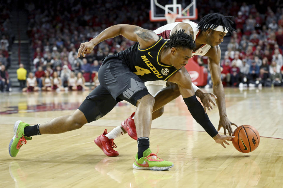 Missouri guard DeAndre Gholston (4) and Arkansas guard Ricky Council IV (1) go after the ball during the first half of an NCAA college basketball game Wednesday, Jan. 4, 2023, in Fayetteville, Ark. (AP Photo/Michael Woods)