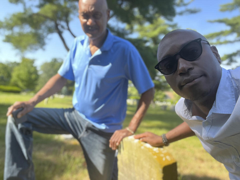 The Associated Press religion reporter Darren Sands and his father, Lonnie Sands, pose by the gravestone of his great-great-great-great-grandfather and Civil War soldier Hewlett Sands in Westbury, N.Y., Monday, June 17, 2024. Hewlett Sands, born into slavery, served in the 26th United States Colored Infantry. He will be honored in a Juneteenth ceremony in Washington, D.C., along with about 200,000 other Black soldiers who fought to preserve the Union. (AP Photo/Darren Sands)