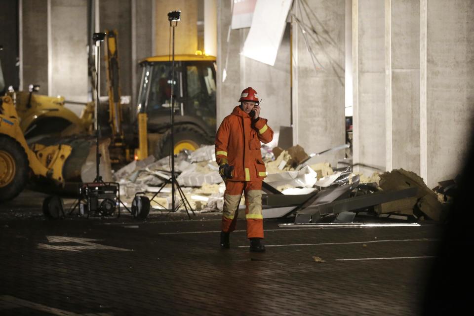 An emergency service personnel speaks on his mobile phone as he walks past the collapsed Maxima supermarket in Riga