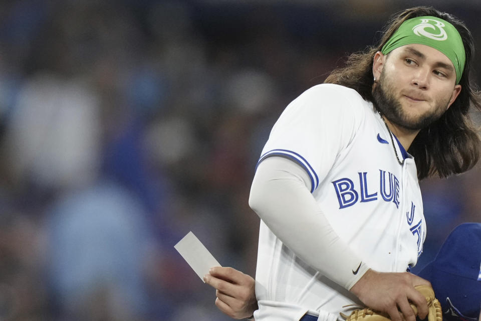 Toronto Blue Jays shortstop Bo Bichette passes a note to teammate Matt Chapman as he stands on the mound during a pitching change during the sixth inning of the team's baseball game against the Tampa Bay Rays on Friday, Sept. 29, 2023, in Toronto. (Chris Young/The Canadian Press via AP)