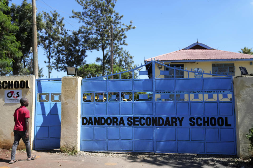 A student enters the Dandora Secondary school in the capital Nairobi, Kenya Monday, April 22, 2024. Students at a school next to Kenya's largest dumpsite are on a mission to try to purify the air with bamboo. They have planted more than 100 seedlings along the wall that separates the school from the trash dump that was declared full 23 years ago. (AP Photo/Brian Inganga)