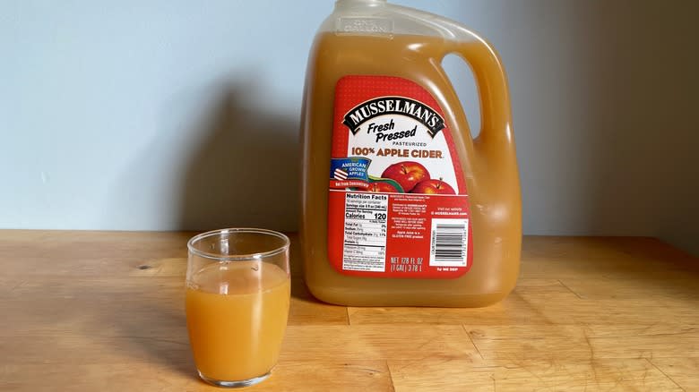 Large container of Musselman's cider with glass cup