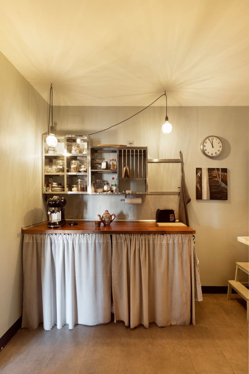 Food storage hung on wall behind skirted counter in neutral toned kitchen.