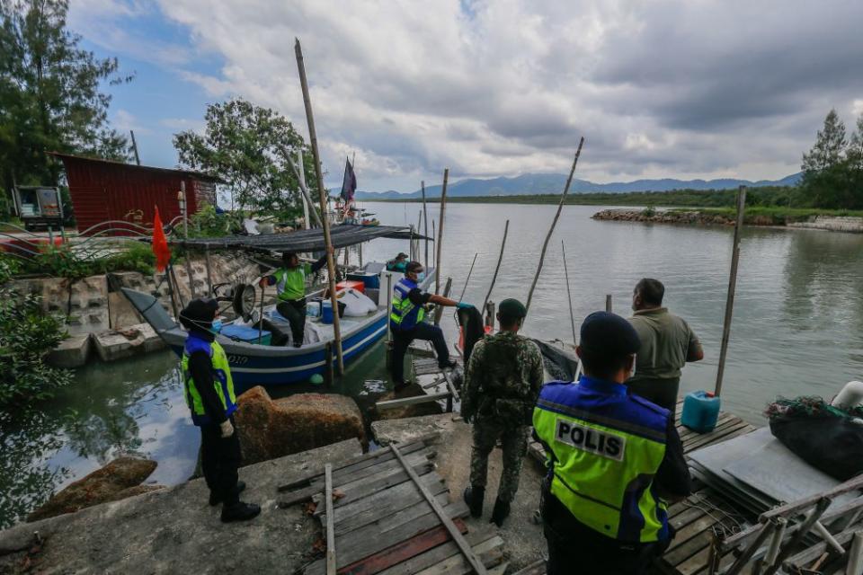 Police and Armed Forces personnel conduct checks on a fishing boat in Kampung Pulau Betong in Balik Pulau April 8, 2020. — Picture by Sayuti Zainudin