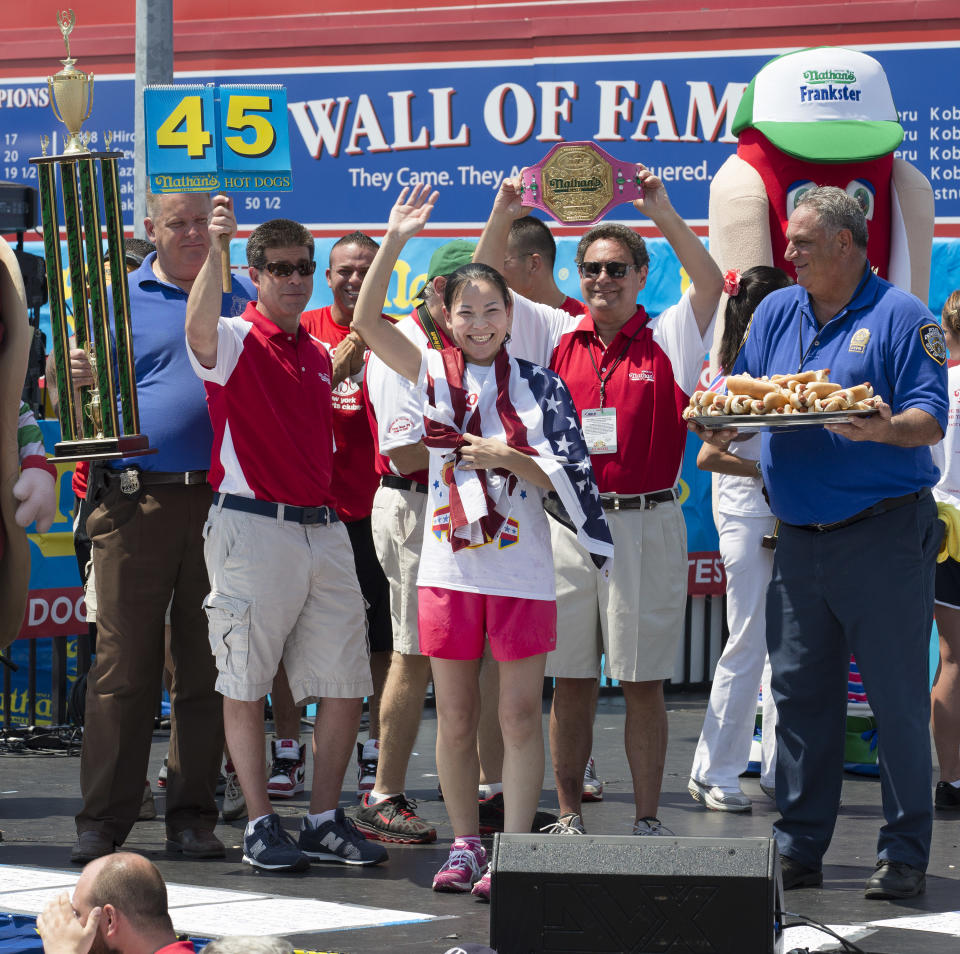 Sonya "The Black Widow" Thomas accepts her trophy after she wins Nathan's Famous Women's Hot Dog Eating World Championship, Wednesday, July 4, 2012, at Coney Island, in the Brooklyn borough of New York. Thomas beat her own record by gobbling down 45 hot dogs and buns in 10 minutes to win the women's competition at the annual Coney Island contest. (AP Photo/John Minchillo)