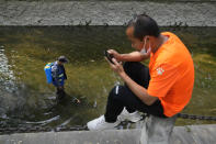 A worker wearing a mask disinfects a canal on Thursday, May 19, 2022, in Beijing. (AP Photo/Ng Han Guan)