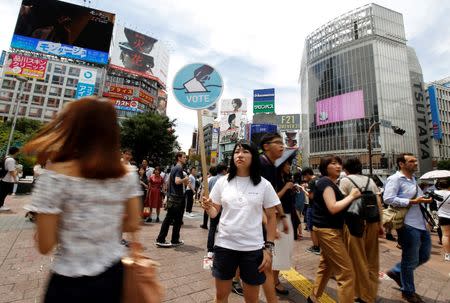 A member of the Students Emergency Action for Liberal Democracy (SEALDs) holds a placard calling on youths to vote in the July 10 upper house election, in front of a busy crossing in Shibuya district in Tokyo, Japan June 26, 2016. REUTERS/Toru Hanai