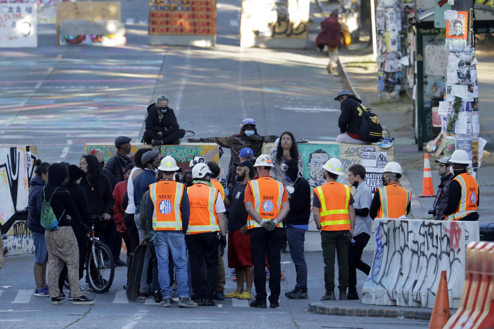 Seattle Department of Transportation workers talk with protest organizers near the Seattle Police Department East Precinct building after SDOT arrived at the the CHOP (Capitol Hill Occupied Protest) zone in Seattle, Friday, June 26, 2020, with the intention of removing barricades that had been set up in the area. Several blocks in the area have been occupied by protesters since Seattle Police pulled back from their East Precinct building following violent clashes with demonstrators earlier in the month. (AP Photo/Ted S. Warren)