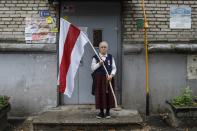 Nina Bahinskaya, 73, poses for a photo holding an old Belarusian national flag at an entrance of her apartment building in Minsk, Belarus, Thursday, Sept. 10, 2020. The 73-year-old former geologist has become one of the most recognizable faces of Belarus protests, fearlessly waving a huge opposition's red-and-white flag in front of riot police.