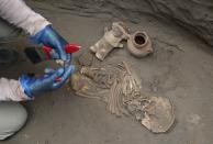 In this Feb. 12, 2020 photo, an archaeologist handles ancient bones and vessels from a previous Inca culture that were discovered by workers building a new natural gas line through the Puente Piedra neighborhood of Lima, Peru. About 300 archaeological finds, some 2,000 years old, have been reported over the past decade during the building of thousands of kilometers (miles) of natural gas pipelines in the capital. (AP Photo/Martin Mejia)