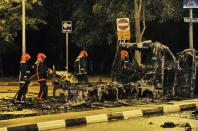 Firemen douse a charred ambulance after a riot broke out in Singapore, in the early hours of December 9, 2013