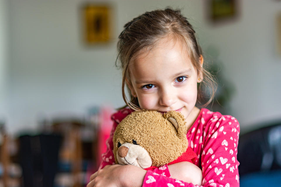 A young girl holding her teddy bear