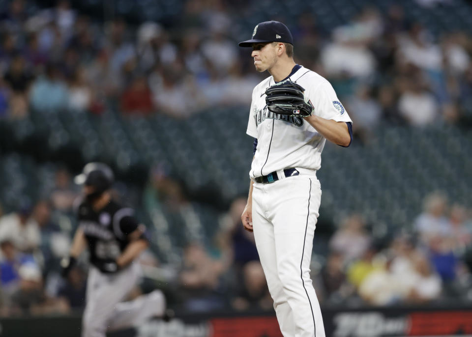 Seattle Mariners starting pitcher Chris Flexen reacts on the mound after giving up a solo home run to Colorado Rockies' C.J. Cron, passing in the background during the seventh inning of a baseball game, Tuesday, June 22, 2021, in Seattle. (AP Photo/John Froschauer)