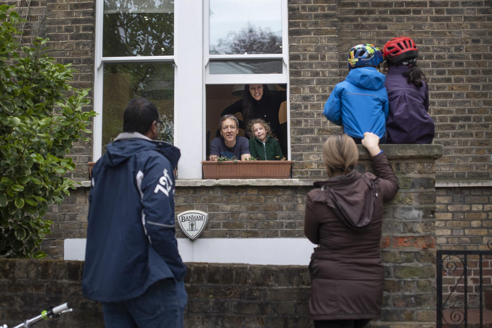 Two families who gave permission to be photographed, maintain social distancing while talking to each other outside a home in Hampstead, north London, Sunday May 3, 2020, as the UK continues in lockdown to help curb the spread of the coronavirus. The highly contagious COVID-19 coronavirus has impacted on nations around the globe, many imposing self isolation and exercising social distancing when people move from their homes. (Victoria Jones / PA via AP)