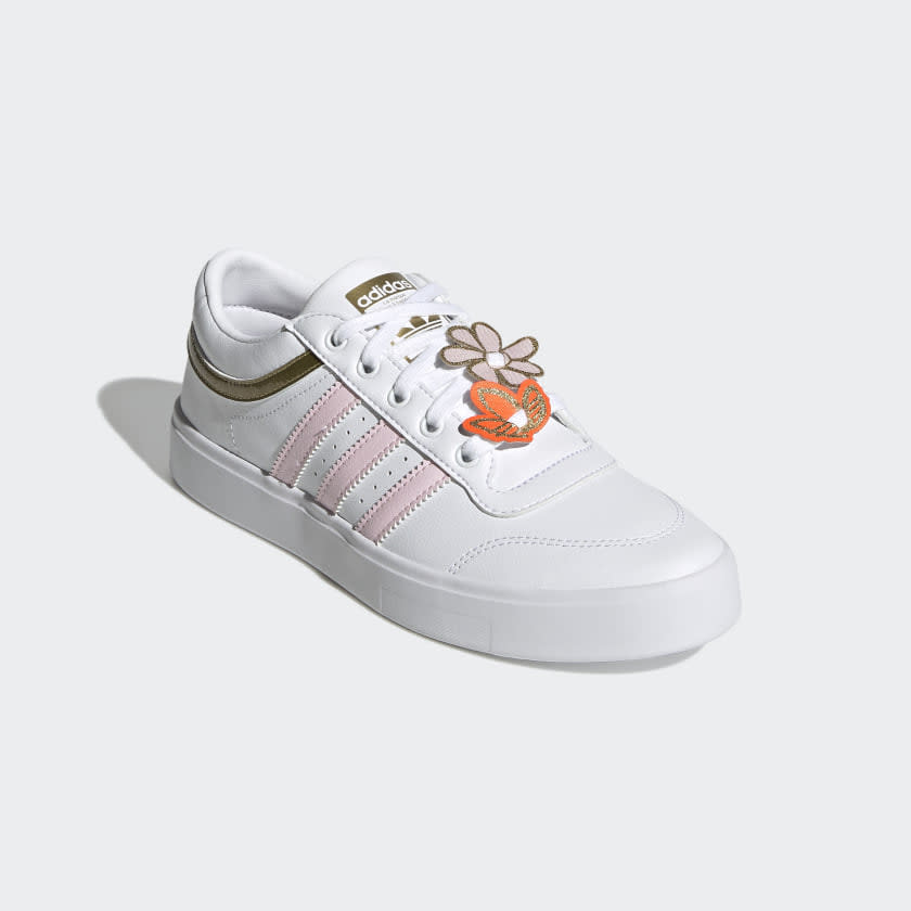 White sneakers with pink stripes, gold heal and flower accents.