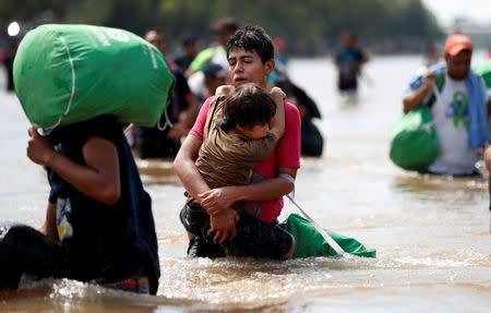 Migrants, part of a caravan traveling to the U.S., struggle to cross the river from Guatemala to Mexico in Ciudad Hidalgo and continue to walk in Mexico, October 29, 2018. REUTERS/Leah Millis/File photo