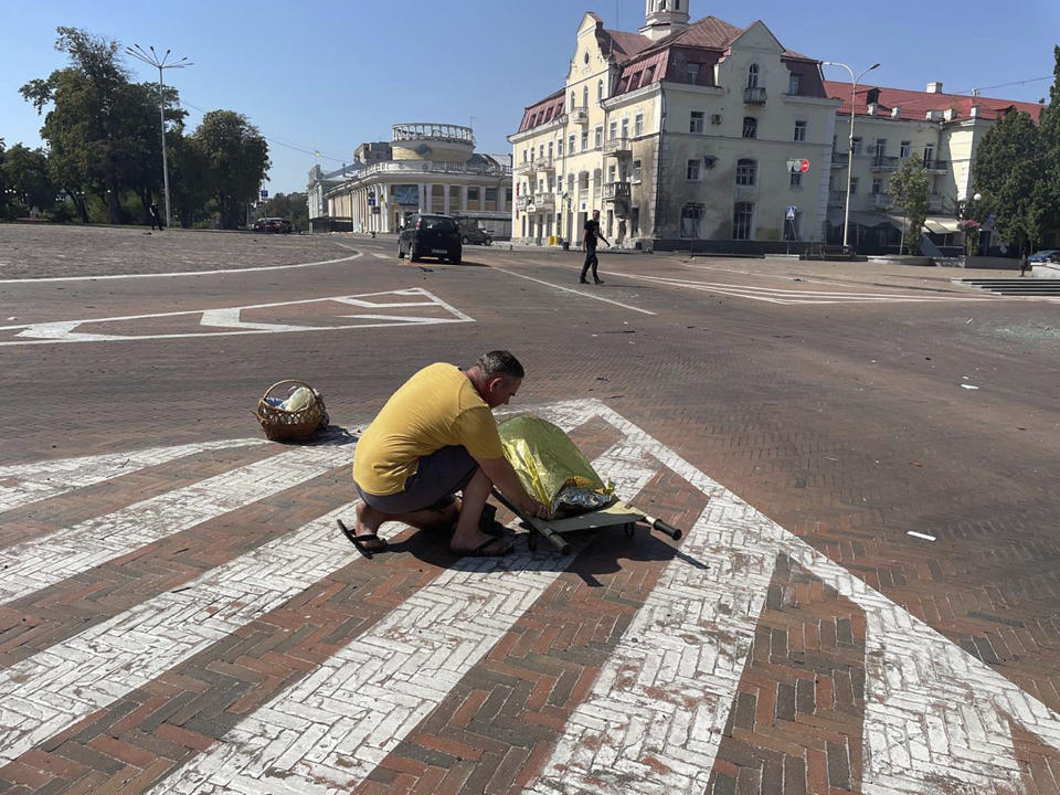 In this photo provided by the National Police of Ukraine, a man covers a dead body after a Russian attack, in Chernihiv, Ukraine, Saturday, Aug. 19, 2023. (National Police of Ukraine via AP)