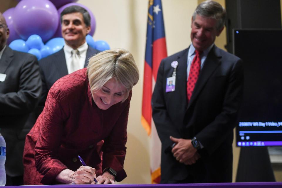 Wellstar President and CEO Candice Saunders signs documents during the Wellstar and Augusta University Health System merger signing ceremony at Augusta University on Wednesday, Aug. 30, 2023.