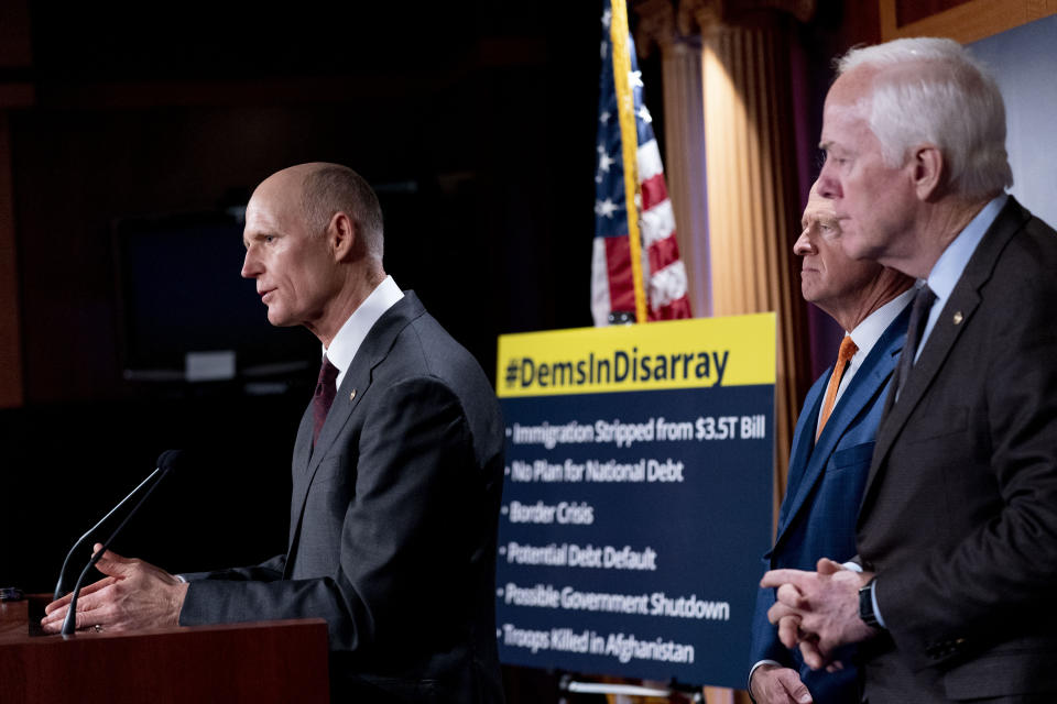 A sign reads "#DemsinDisarray" as Sen. Rick Scott, R-Fla., left, accompanied by Sen. Pat Toomey, R-Pa., second from right, and Sen. John Cornyn, R-Texas, right, speaks at a news conference to speak out against the Democrats on numerous issues, on Capitol Hill in Washington, Wednesday, Sept. 29, 2021. (AP Photo/Andrew Harnik)