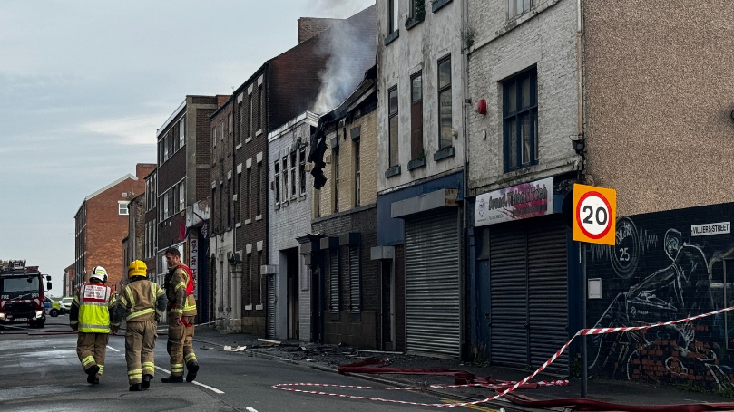 Smoke rises from a building on Villiers Street, firefighters stand outside
