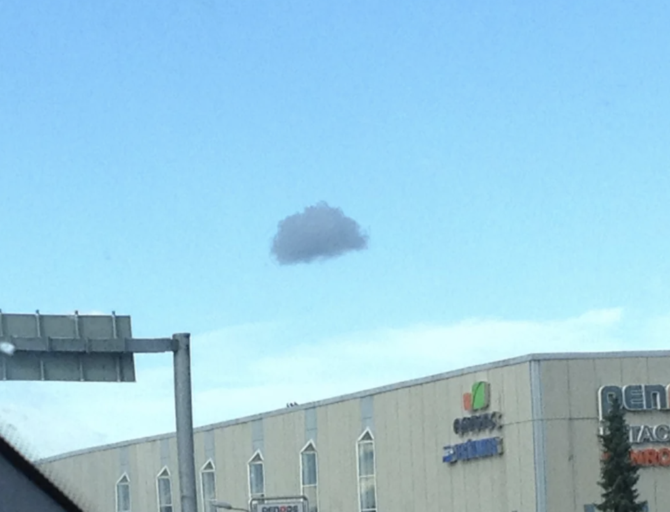 Unidentified object in the sky behind building, possibly a weather phenomenon