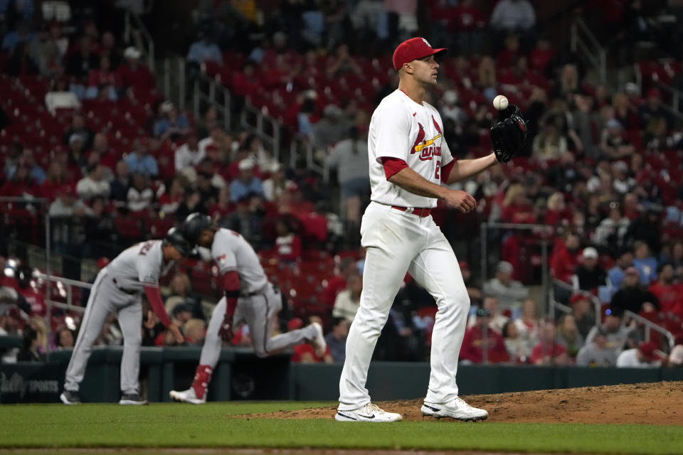 St. Louis Cardinals starting pitcher Jack Flaherty, right, tosses a ball in the air as Arizona Diamondbacks' Ketel Marte is congratulated by third base coach Tony Perezchica, left, while rounding the bases after hitting a solo home run during the seventh inning of a baseball game Monday, April 17, 2023, in St. Louis. (AP Photo/Jeff Roberson)