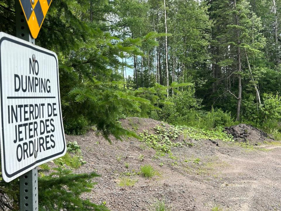 A pile of asphalt dumped a few metres from a no dumping sign.