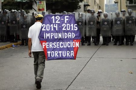 A man walks with a kite in front of national guards during a march against Venezuelan President Nicolas Maduro's government in Caracas February 12, 2015. REUTERS/Jorge Silva