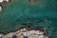 People swim in the sea at Vouliagmeni suburb, southwest of Athens, on Thursday, July 29, 2021. One of the most severe heat waves recorded since 1980s scorched southeast Europe on Thursday, sending residents flocking to the coast, public fountains and air-conditioned locations to find some relief, with temperatures rose above 40 C (104 F) in parts of Greece and across much of the region. (AP Photo/Yorgos Karahalis)