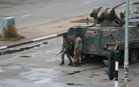 A military tank is seen with armed soldiers on the road leading to President Robert Mugabe's office in Harare on Wednesday morning - Credit: AP