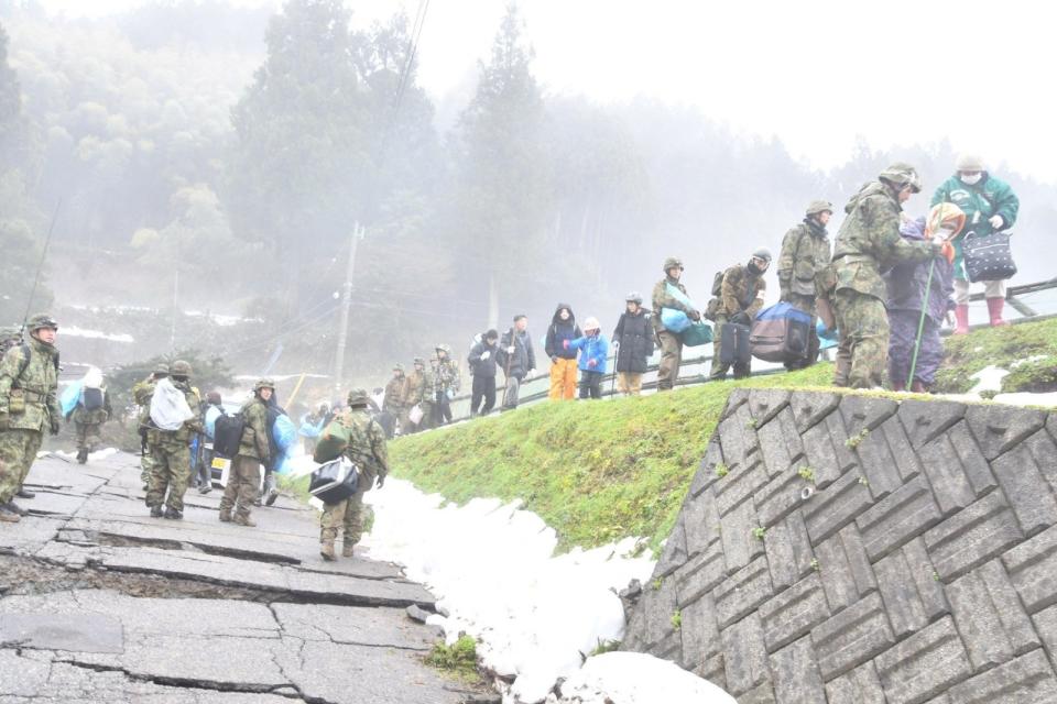 日本石川縣輪島市部分道路在強震後受損嚴重，自衛隊成員協助偏遠地區居民撤離。路透社