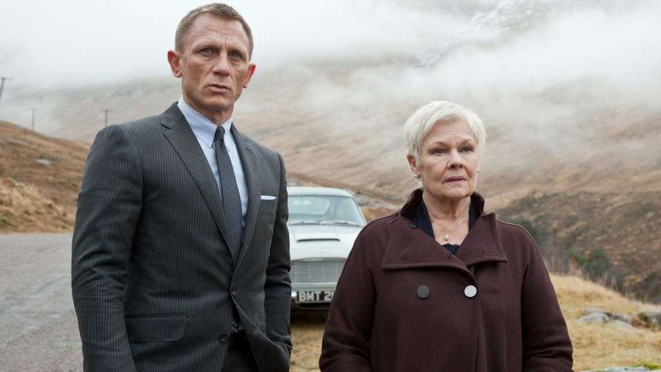 Daniel Craig and Dame Judi Dench stand together in the countryside in Skyfall.