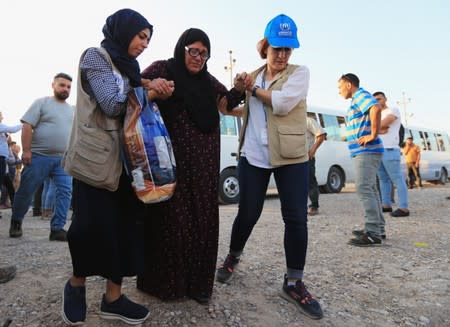 U.N. workers help a Syrian displaced woman, who fled violence after the Turkish offensive against Syria, upon arrival at a refugee camp in Bardarash on the outskirts of Dohuk