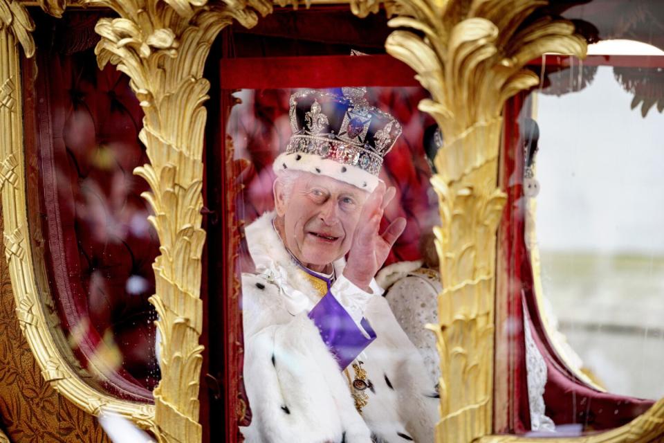 Britain's King Charles III greets the crowd as he travels in the Gold State Coach