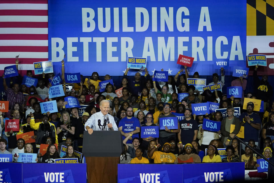 President Biden, looking cheerful, is surrounded by supporters beneath a banner saying: Building a Better America.