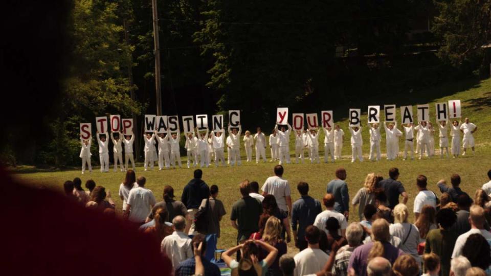 People dressed entirely in white hold up signs with letters that read 