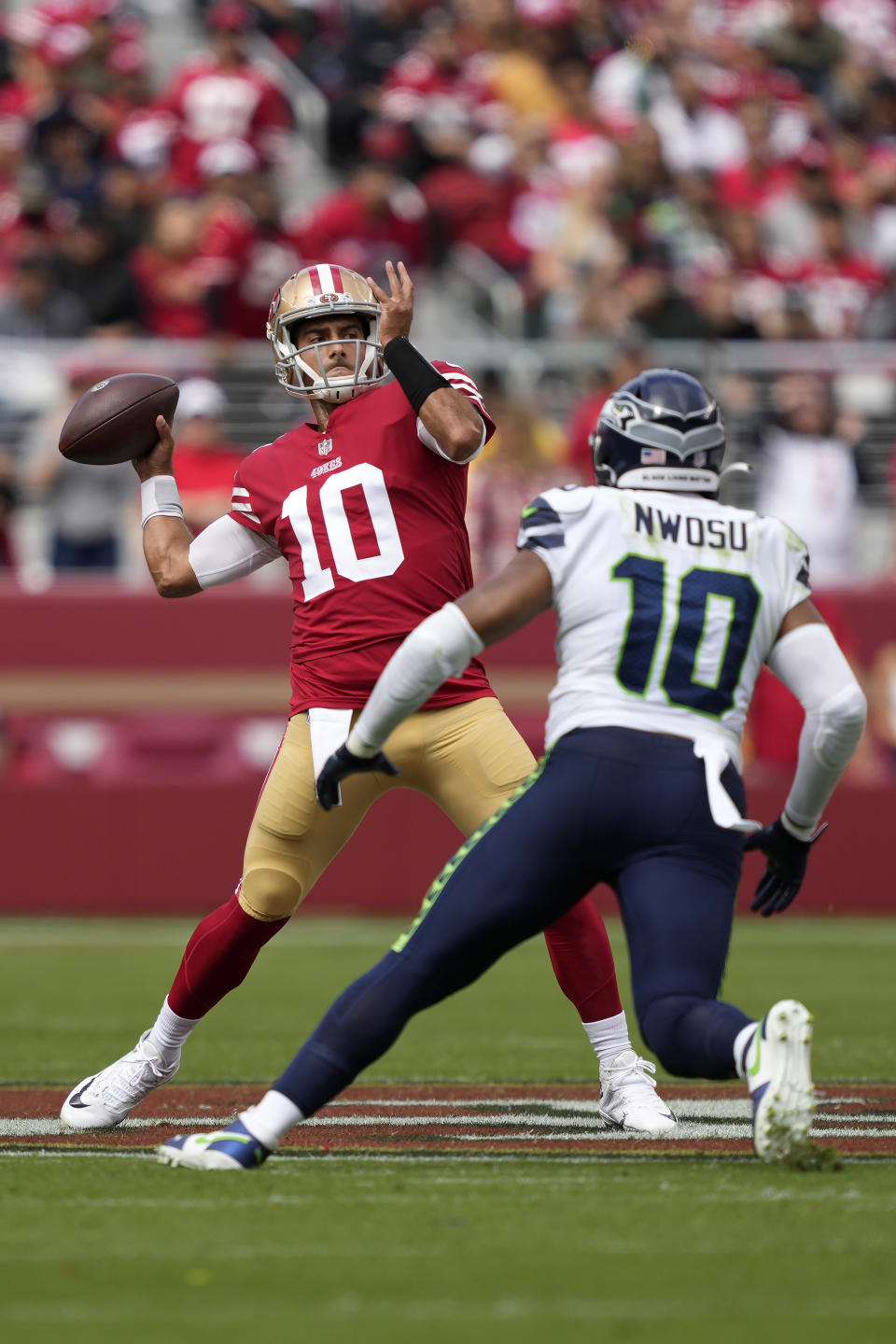 San Francisco 49ers quarterback Jimmy Garoppolo, left, passes against Seattle Seahawks linebacker Uchenna Nwosu during the first half of an NFL football game in Santa Clara, Calif., Sunday, Sept. 18, 2022. (AP Photo/Tony Avelar)