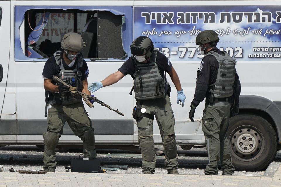 Israeli police retrieve weapons used by militants outside a police station that was overrun by Hamas gunmen on Saturday, in Sderot, Israel, Sunday, Oct.8, 2023. Hamas militants stormed over the border fence Saturday, killing hundreds of Israelis in surrounding communities. (AP Photo/Ohad Zwigenberg)