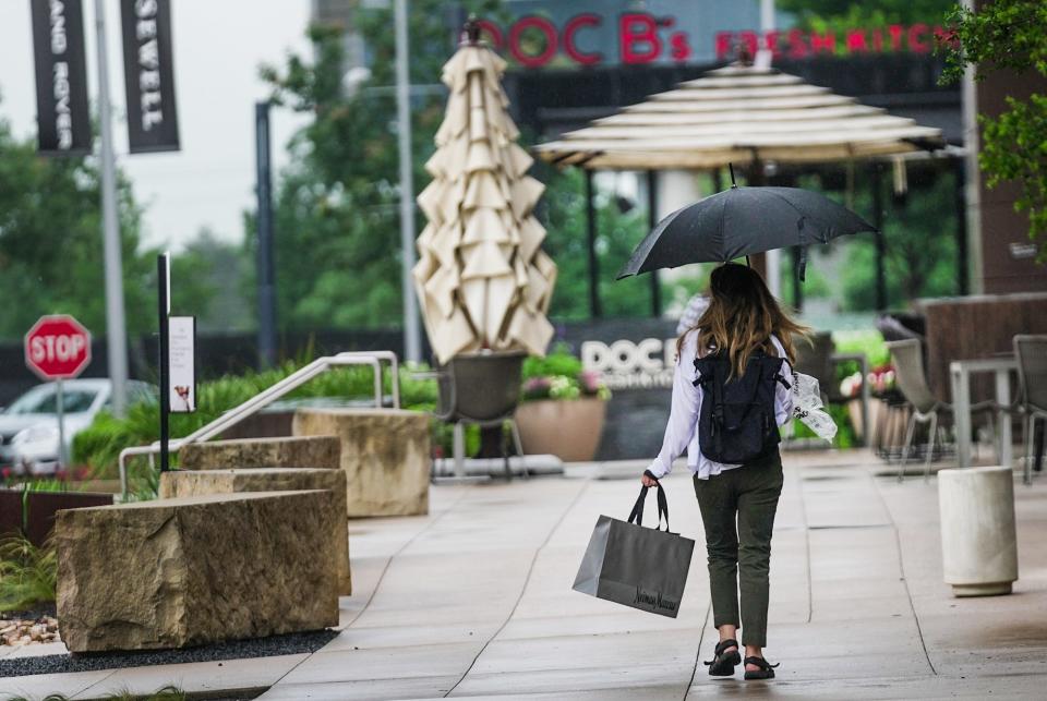 Sarah Makowsky shields herself from the rain as she makes her way through the Domain last month. More storms are headed to Central Texas this week.