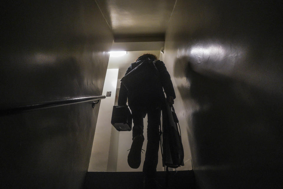 Josh Spodek carries a portable solar kit from his fifth floor apartment up eleven flight of stairs to the rooftop, where he will solar charge his laptop and phone, Tuesday Jan. 24, 2023, in New York. Spodek, who teaches leadership as an adjunct professor at New York University, believes it's a reasonable option in the quest to reduce energy usage and live more sustainably. "When I'm climbing up the stairs, my heart is with indigenous people around the world," said Spodek. (AP Photo/Bebeto Matthews)