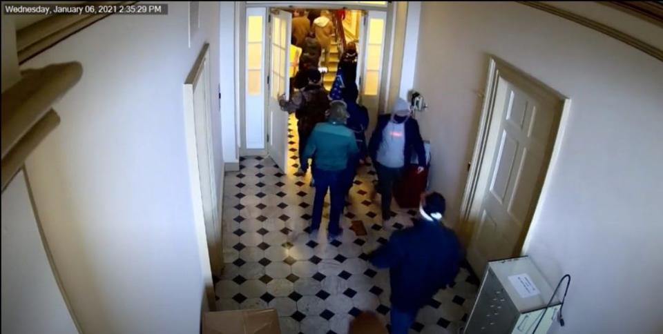 Capitol security footage from Jan. 6. This angle shows the man in the blue coat, who is also wearing pink shoes, turn around and walk back down the corridor.