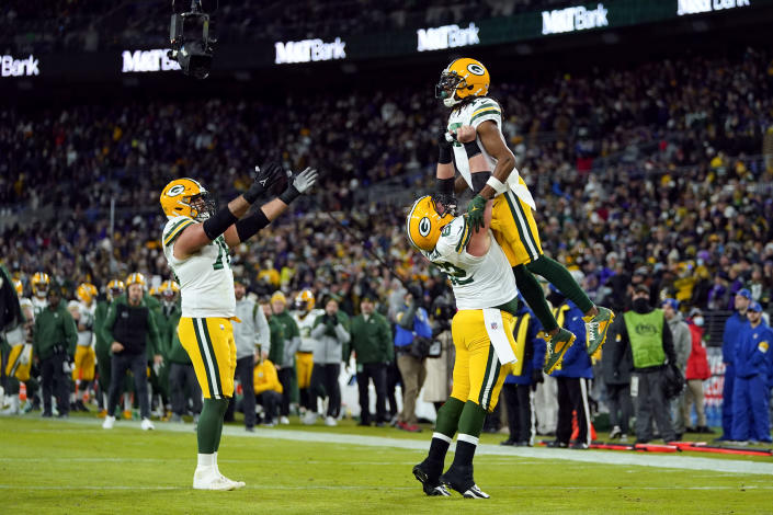 Green Bay Packers wide receiver Davante Adams, top right, celebrates his touchdown with teammates Lucas Patrick, bottom right, and Jon Runyan in the first half of an NFL football game against the Baltimore Ravens, Sunday, Dec. 19, 2021, in Baltimore. (AP Photo/Julio Cortez)