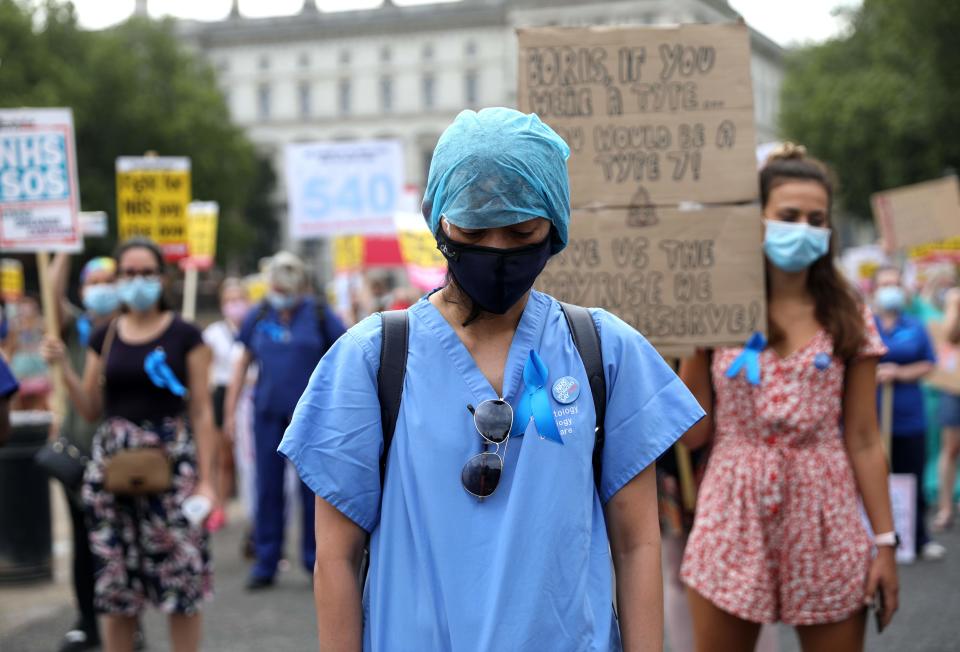 NHS (National Health Service) workers hold a minute's silence to pay tribute to NHS staff who have died with coronavirus during a march through the streets of London on August 8, 2020, to demand a pay rise. (Photo by ISABEL INFANTES / AFP) (Photo by ISABEL INFANTES/AFP via Getty Images)