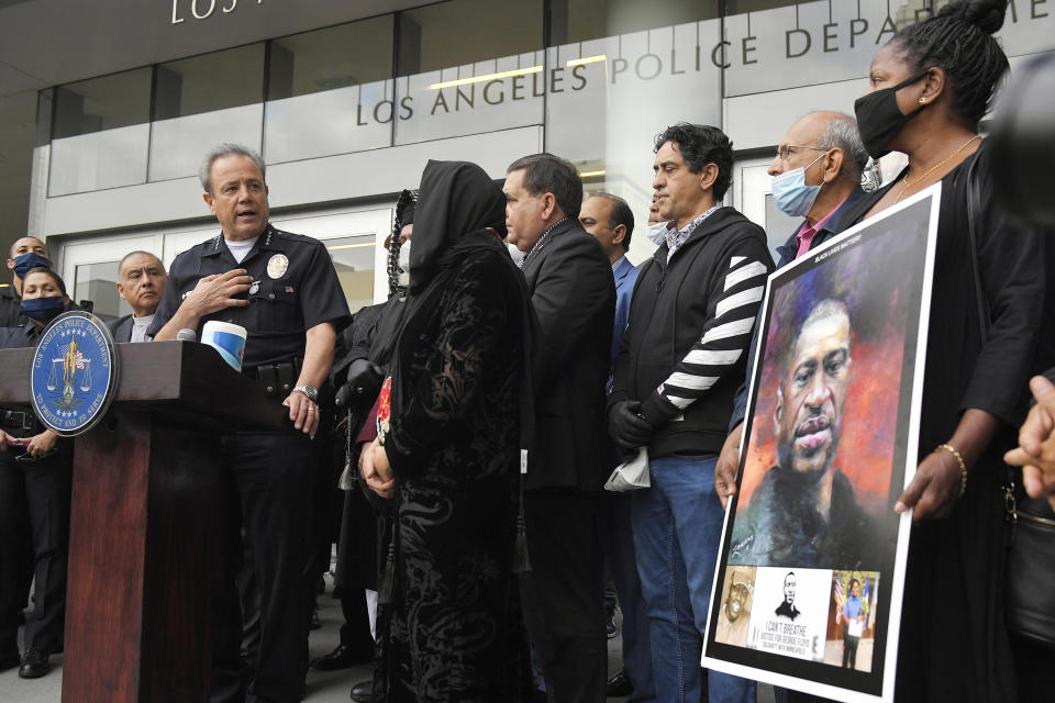 FILE - In this June 5, 2020, file photo, Los Angeles police chief Michel Moore, left, speaks as someone holds up a portrait of George Floyd during a vigil with members of professional associations and the interfaith community at Los Angeles Police Department headquarters in Los Angeles. The Los Angeles Police Department launched an internal investigation after an officer reported that a photo of Floyd with the words "You take my breath away" in a Valentine-like format was circulated among officers, according to a newspaper report. Moore said Saturday, Feb. 12, 2021, that investigators will try to determine how the image may have come into the workplace and who may have been involved, the Los Angeles Times reported. (AP Photo/Mark J. Terrill, File)