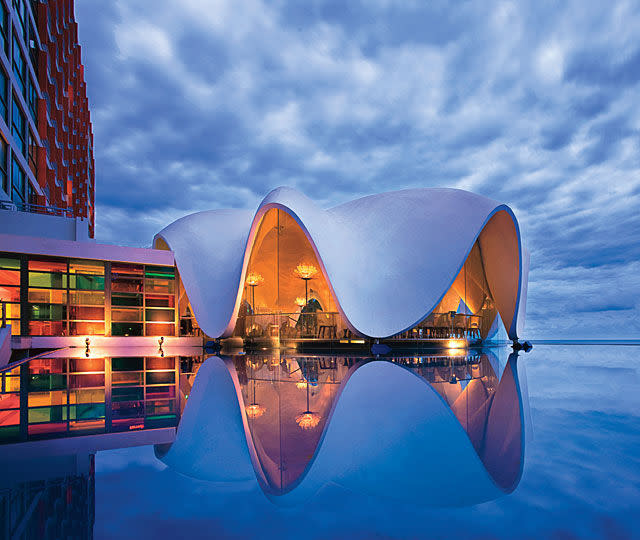 <p>In San Juan, Puerto Rico, you may spot a conch-like structure floating on the coast. It's the famed work of Italian architect Mario Salvadori, who designed the structure (part of La Concha Hotel) in 1958. The shell is situated on an infinity pool elevated above the beach, and inside, a restaurant — <a rel="nofollow noopener" href="http://perlarestaurant.com" target="_blank" data-ylk="slk:La Perla;elm:context_link;itc:0;sec:content-canvas" class="link ">La Perla</a> — offers diners panoramic views of the ocean and beach. </p>