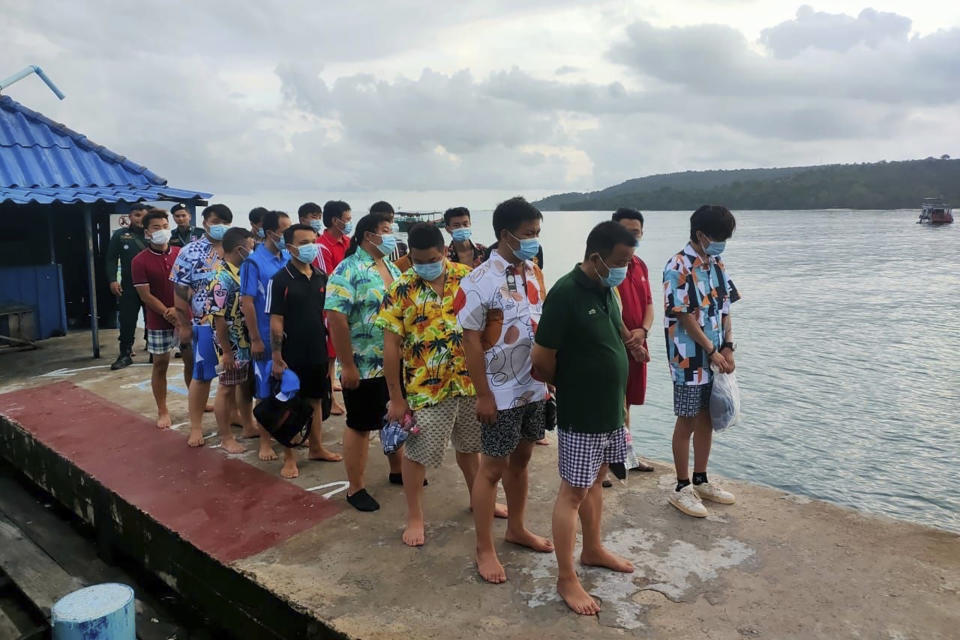 In this photo provided by the Sihanoukville Province Authority Police, Chinese nationals stand on a pier after being rescued from a ship sinking, at an island in Preah Sihanouk Province, southwestern Cambodia on Thursday, Sept. 22, 2022. Cambodian authorities were searching Friday, Sept. 23, for more than 20 people in the Gulf of Thailand after their boat sank near Cambodia's Koh Tang island, authorities said. (Preah Sihanouk province Authority Police via AP)