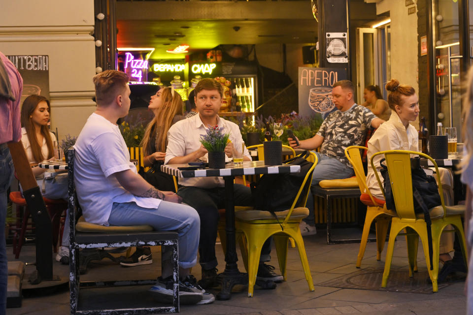 People sit in a cafe in Moscow, Russia, Tuesday, Aug. 1, The glittering towers of the Moscow City business district were once symbols of the Russian capital's economic boom in the early 2000s. Now they are a sign of its vulnerability, following a series of drone attacks that rattled some Muscovites shaken and brought the war in Ukraine home to the seat of Russian power. 2023. (AP Photo/Dmitry Serebryakov)