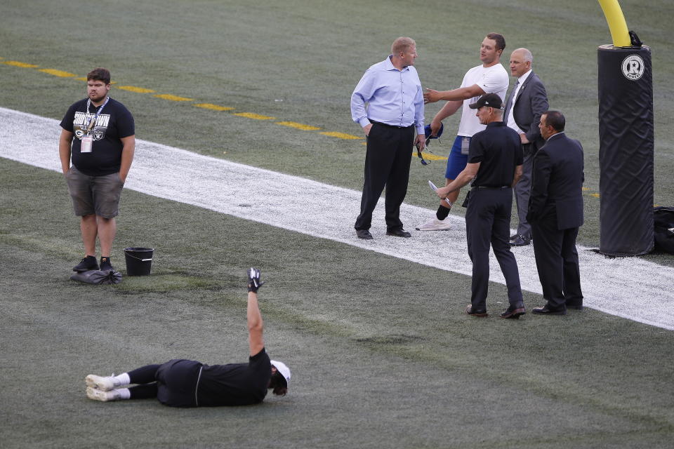 Officials assess the location where the CFL goal post holes were, before an NFL preseason football game between the Oakland Raiders and the Green Bay Packers in Winnipeg, Manitoba, Thursday, Aug. 22, 2019. In the NFL the field goal posts are located at the back of the end zone and the Canadian Football League has the posts at the front of the end zone. (John Woods/The Canadian Press via AP)